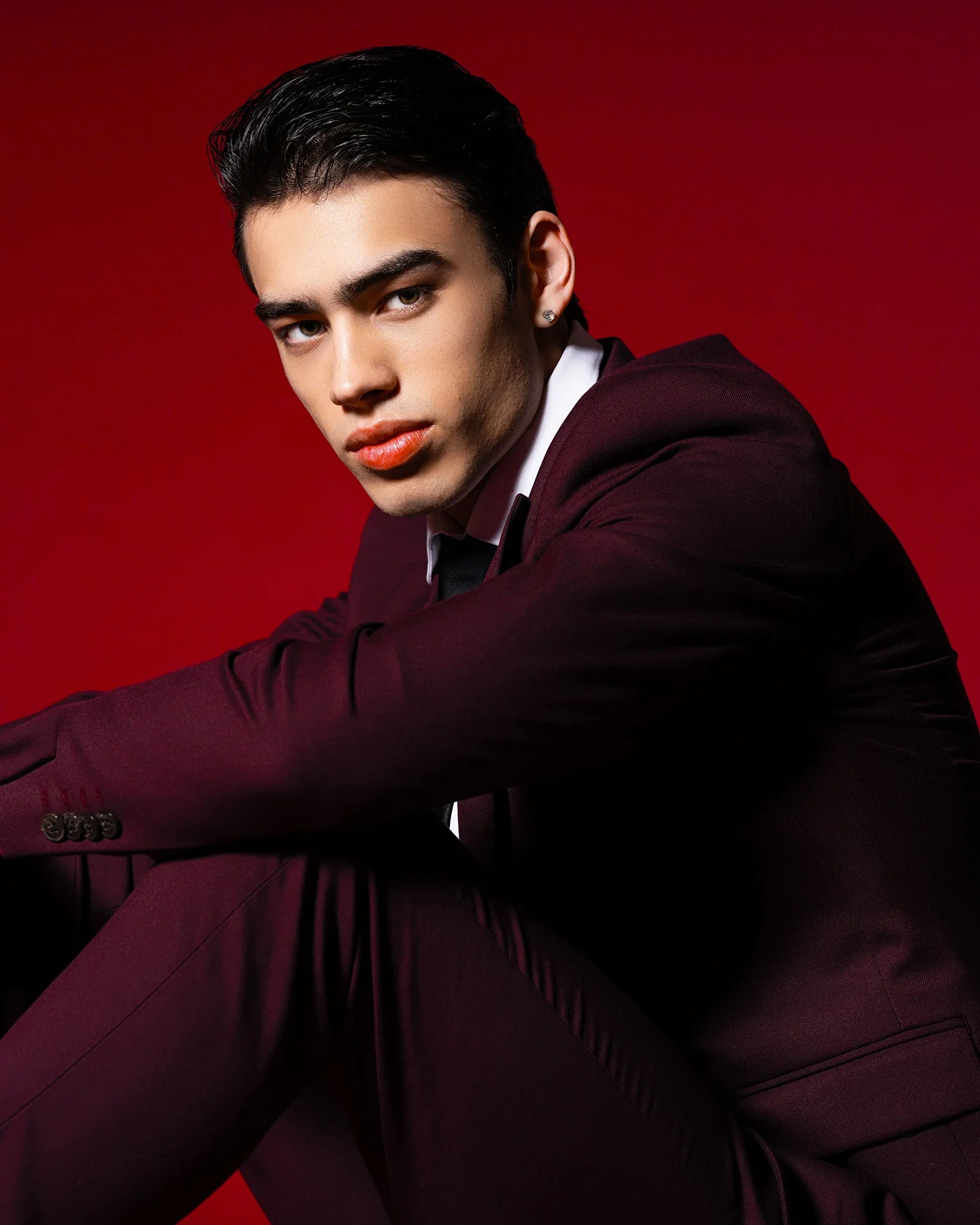 Fashion portrait of Kai in suit against a red backdrop